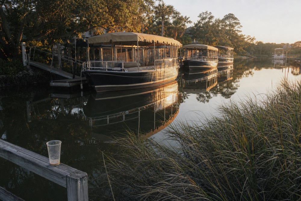 Tour boats anchored along a Mount Pleasant creek at golden hour, no text, no logos, no people