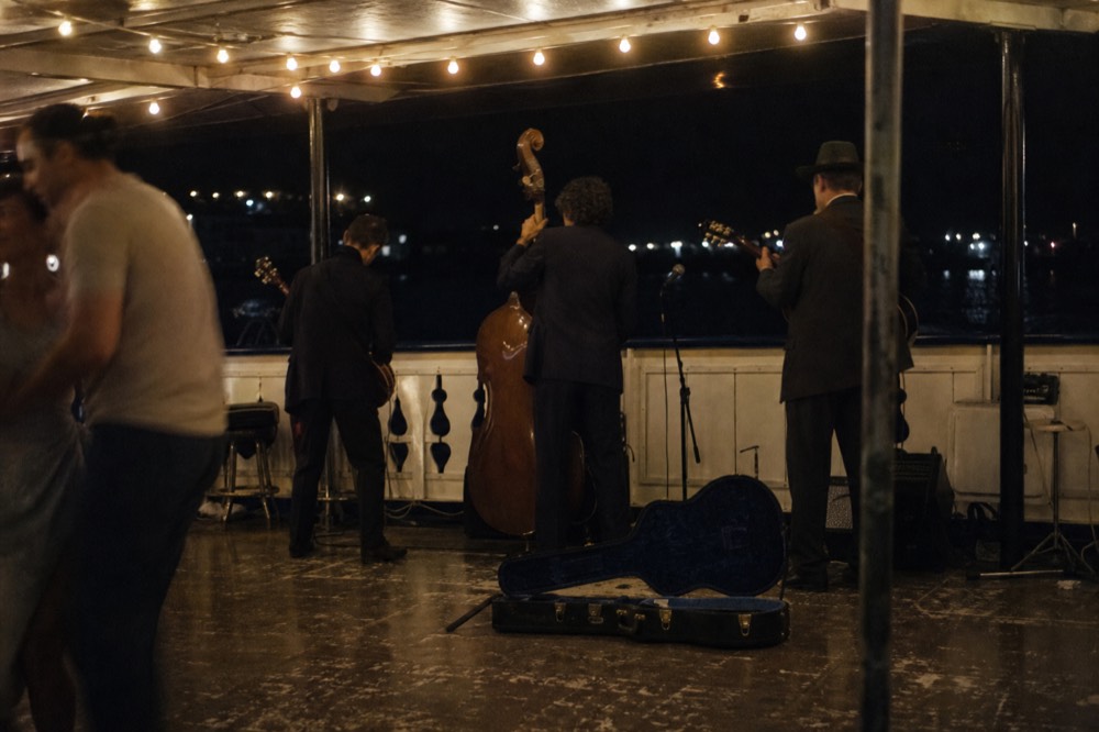 A live band performing on the deck of a harbor dinner cruise, no text, no logos, no people