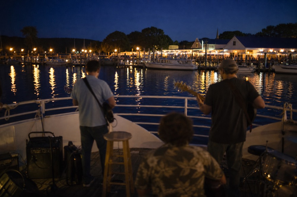 Live musicians performing on the deck of a dinner cruise boat at dusk, no text, no logos, no people