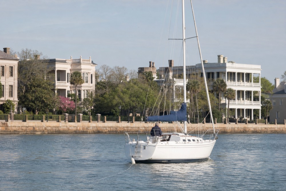 Small sailing yacht underway on calm harbor water near downtown Charleston, no text, no logos, no people
