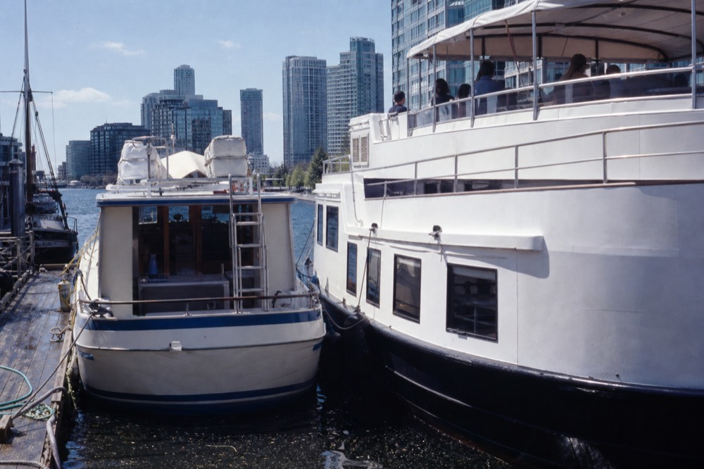 Two tour boats of different sizes moored at a downtown marina dock, no text, no logos, no people.