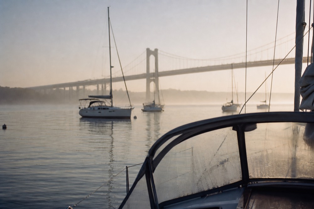 A calm Charleston harbor morning with sailboats and the Ravenel Bridge in soft light, no text, no logos, no people