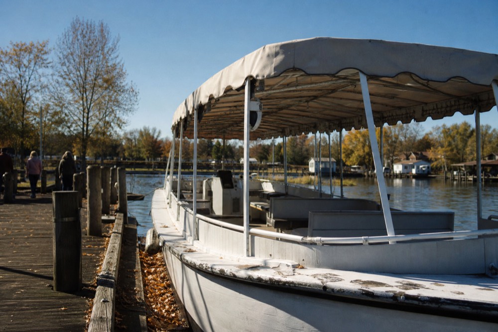 A shaded tour boat docked at a Charleston marina under a clear autumn sky, no text, no logos, no people