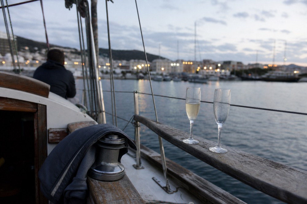 A couple's champagne glasses on the wooden rail of a sailboat at dusk, no text, no logos, no people