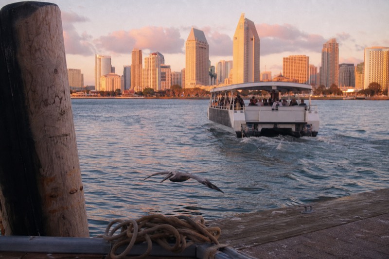 Tour boat easing away from the Charleston Maritime Center at golden hour with the downtown skyline glowing behind it