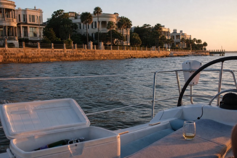 Small private sailing yacht passing the Charleston Battery mansions at summer dusk on a BYOB sunset sail